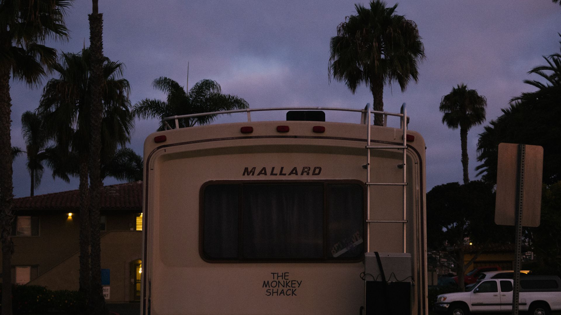 A retro RV parked under palm trees at dusk, capturing a tranquil outdoor scene.