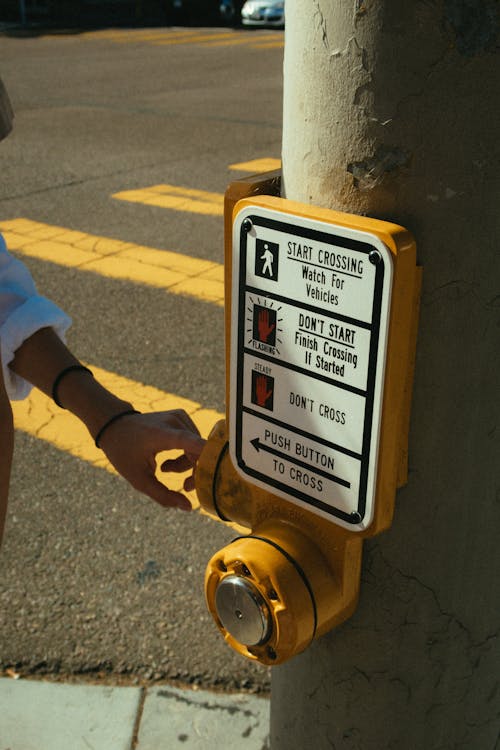 Photo of Person's Hand Near the Warning Sign