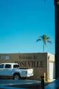 蓝天下的罗斯维尔街景欢迎标志旁，停着一辆皮卡车，还有棕榈树