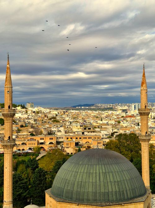 Free Aerial view of a cityscape with minarets and a mosque under a dramatic cloudy sky. Stock Photo