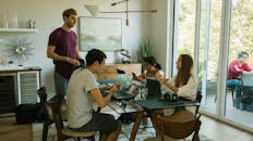 一群年轻人在室内用笔记本电脑和其他设备合作