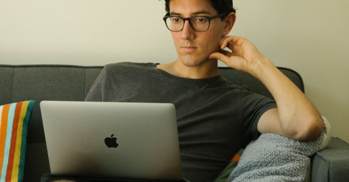 Man Using Macbook While Sitting On Sofa · Free Stock Photo