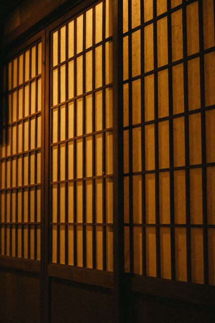 Warmly lit traditional wooden shoji doors, showcasing geometric patterns and Japanese design.