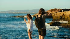 一对男女在岩石海岸欣赏着令人惊叹的海景，捕捉回忆