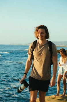 一位轻松的摄影师在日落时分的海边用相机拍摄，散发着幸福与风格