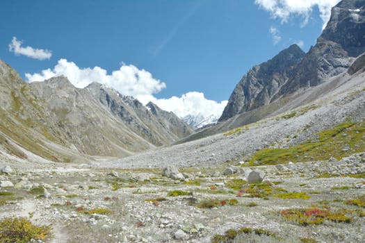Explore the breathtaking rocky terrain and majestic peaks of the Himalayan valley under a bright blue sky.