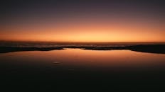 日落时分，海面宁静，充满活力的天空倒映在水中