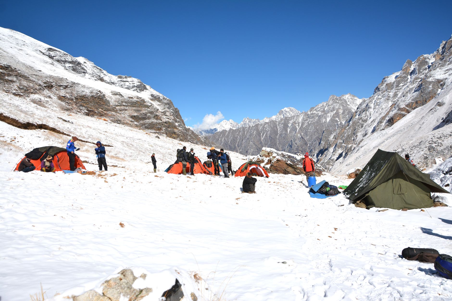 Trekkers camping in the snowy Himalayas with tents and scenic peaks in the backdrop.