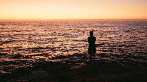 Free Silhouette of a man standing by the ocean at sunset, reflecting tranquility and nature's beauty. Stock Photo
