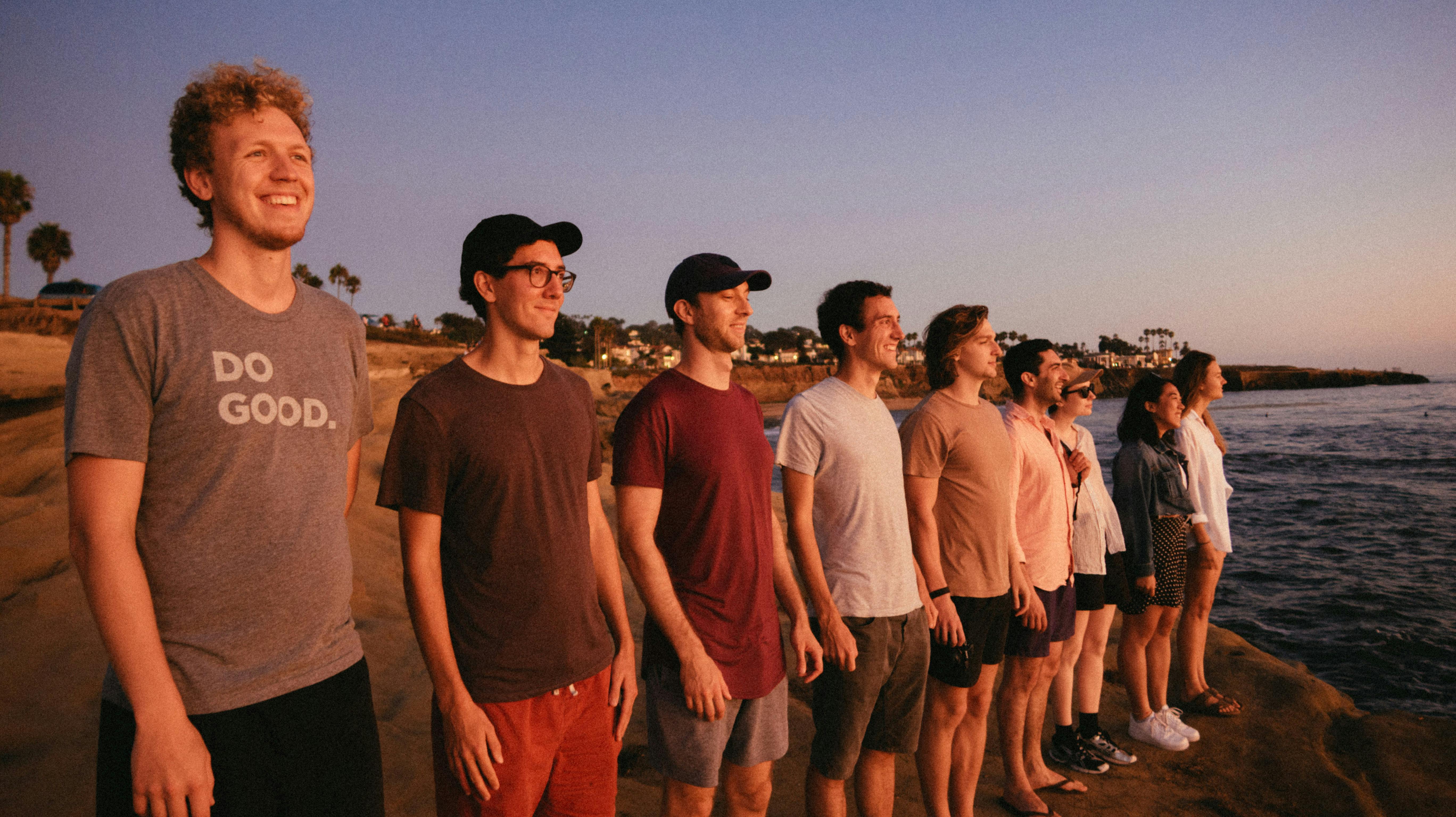 一群朋友在海滩上欣赏日落，这象征着友谊与多样性