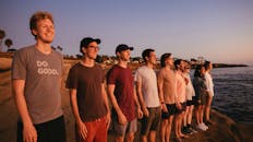 一群朋友在海滩上欣赏日落，这象征着友谊与多样性