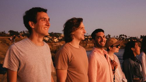 Free A group of friends watching the sunset at the beach, smiling and enjoying the summer evening. Stock Photo