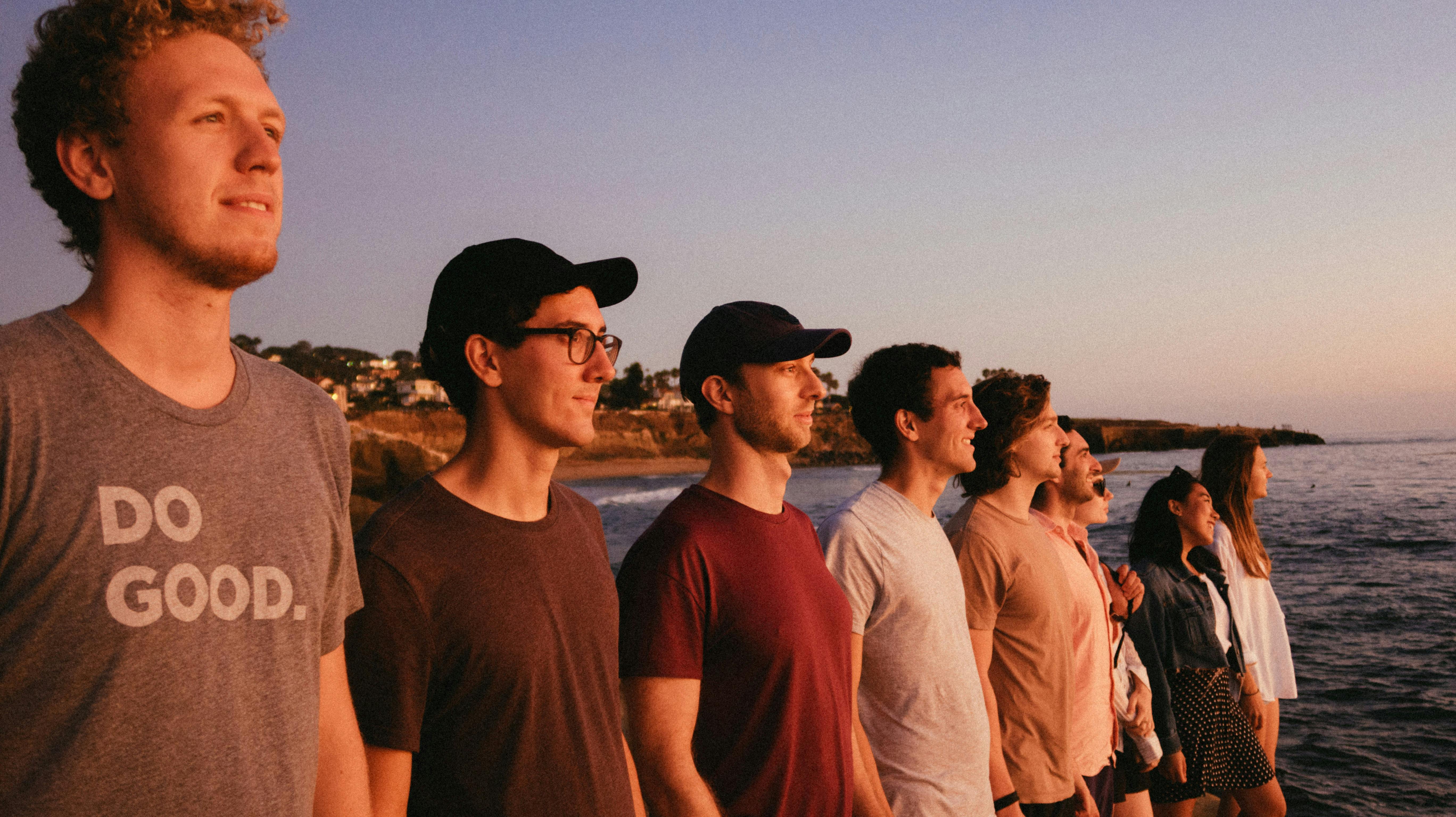 一群朋友在海滩上欣赏宁静的日落，展现了团结与放松