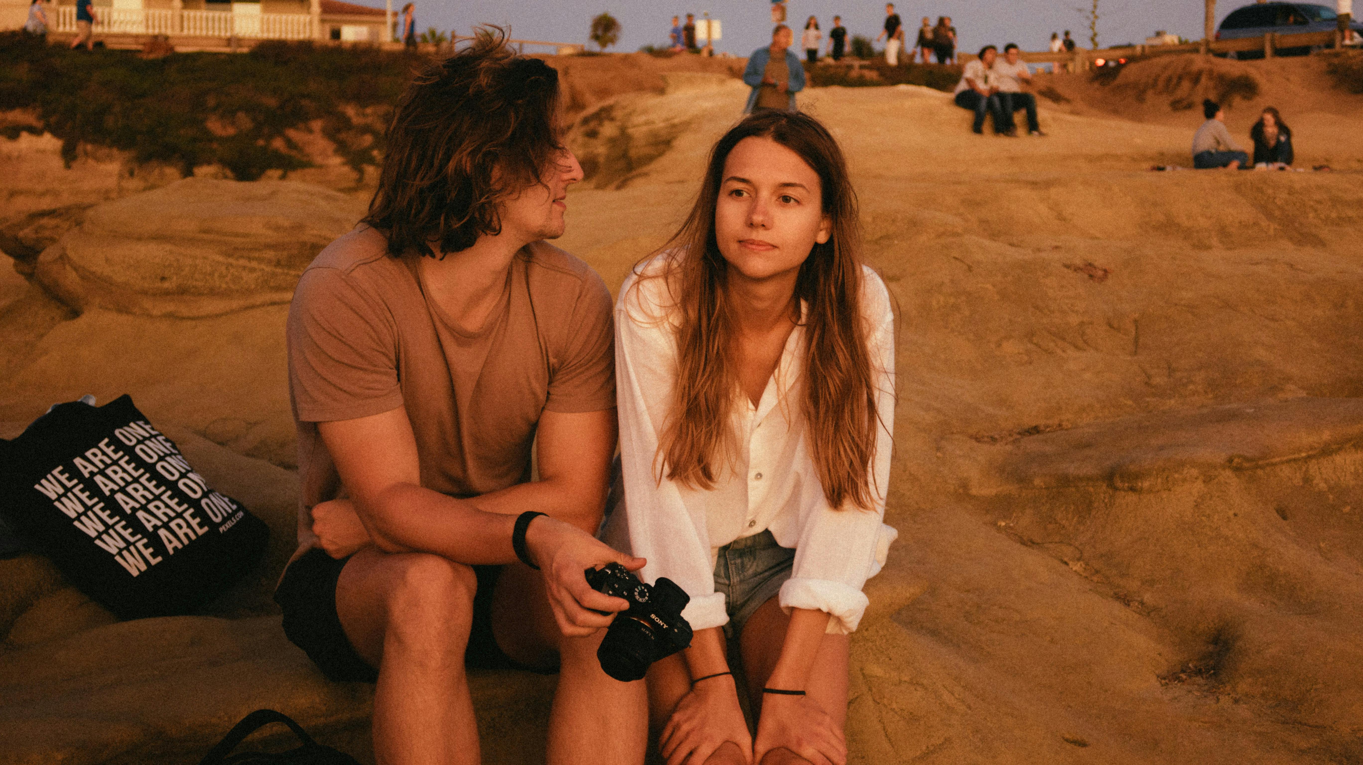 photo of man and woman sitting on sand