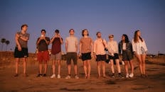 日落时分，一群年轻人站在海滩上，捕捉着友谊的本质