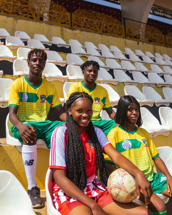 Free Four young soccer players pose in team uniforms inside an empty stadium. Stock Photo