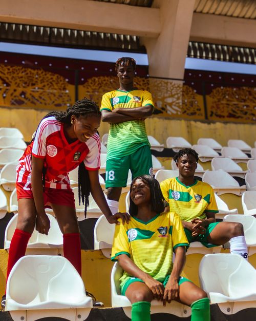 Free Group of female soccer players in vibrant jerseys sharing a moment of camaraderie in a stadium. Stock Photo