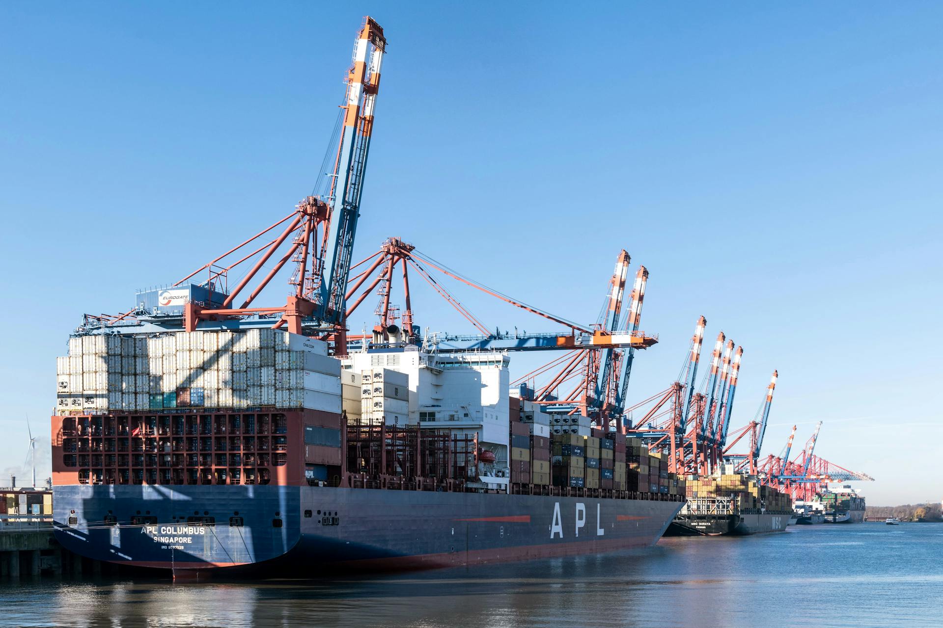 Panorama of container ships and cranes at Hamburg port on a clear day.
