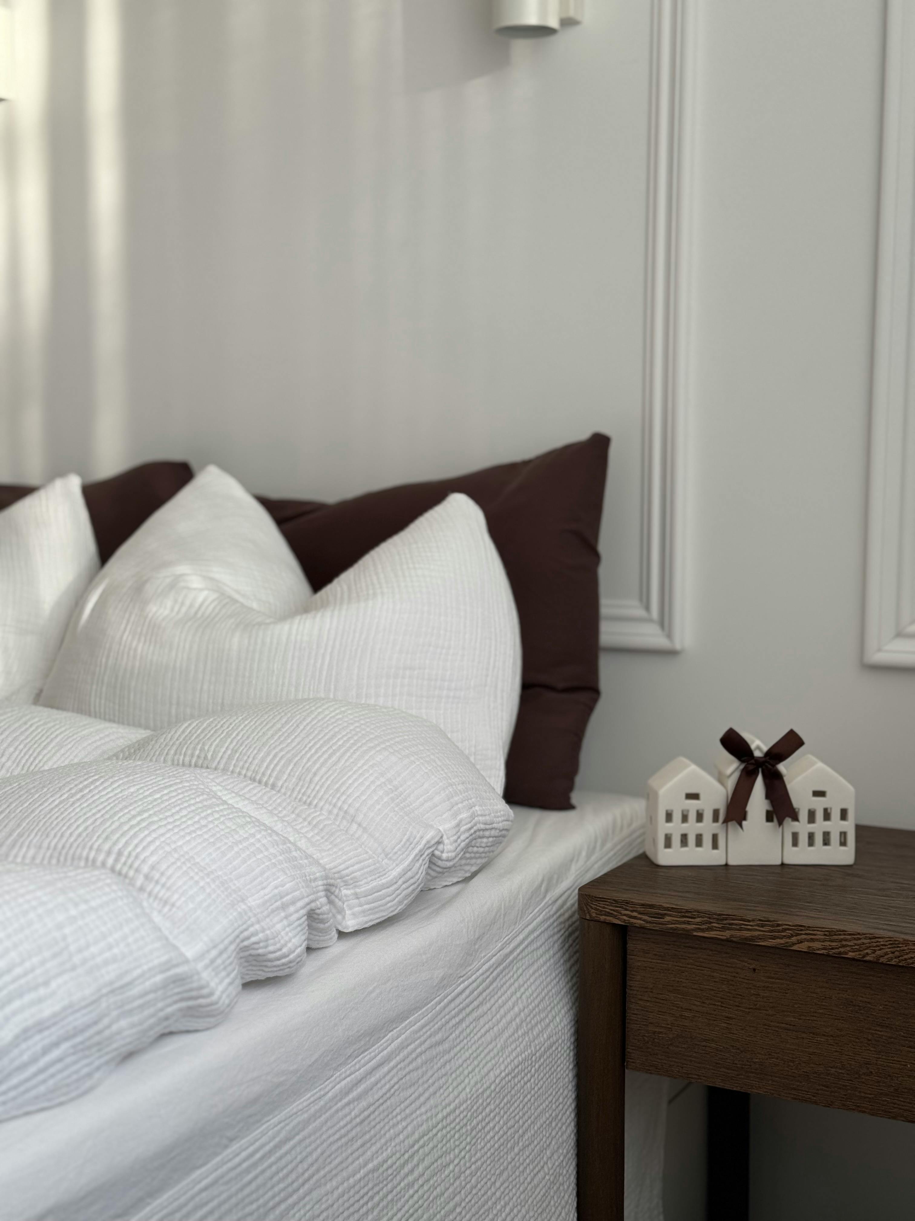 A modern bedroom featuring plush pillows and minimalist decor accents on a side table.