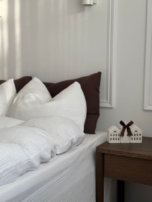 A modern bedroom featuring plush pillows and minimalist decor accents on a side table.