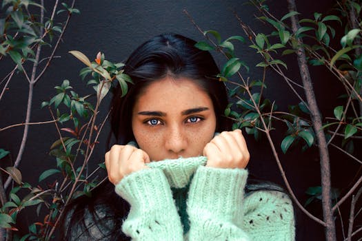 这幅迷人的肖像画描绘了一位蓝眼睛、有雀斑、被树叶环绕的女人