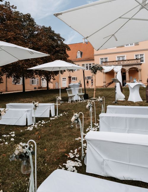Free Beautiful outdoor wedding setting with chairs and umbrellas arranged in a garden. Stock Photo