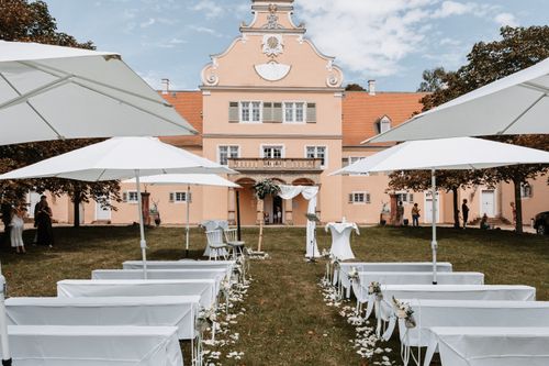 Free Stunning outdoor wedding scene with elegant white decor and a historic backdrop under clear skies. Stock Photo