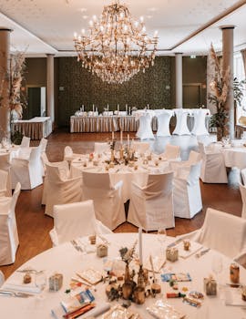Beautifully decorated wedding reception hall with chandeliers, set tables, and elegant decor.
