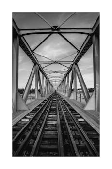 Striking black and white view of a bridge along a railroad track, showcasing symmetry.