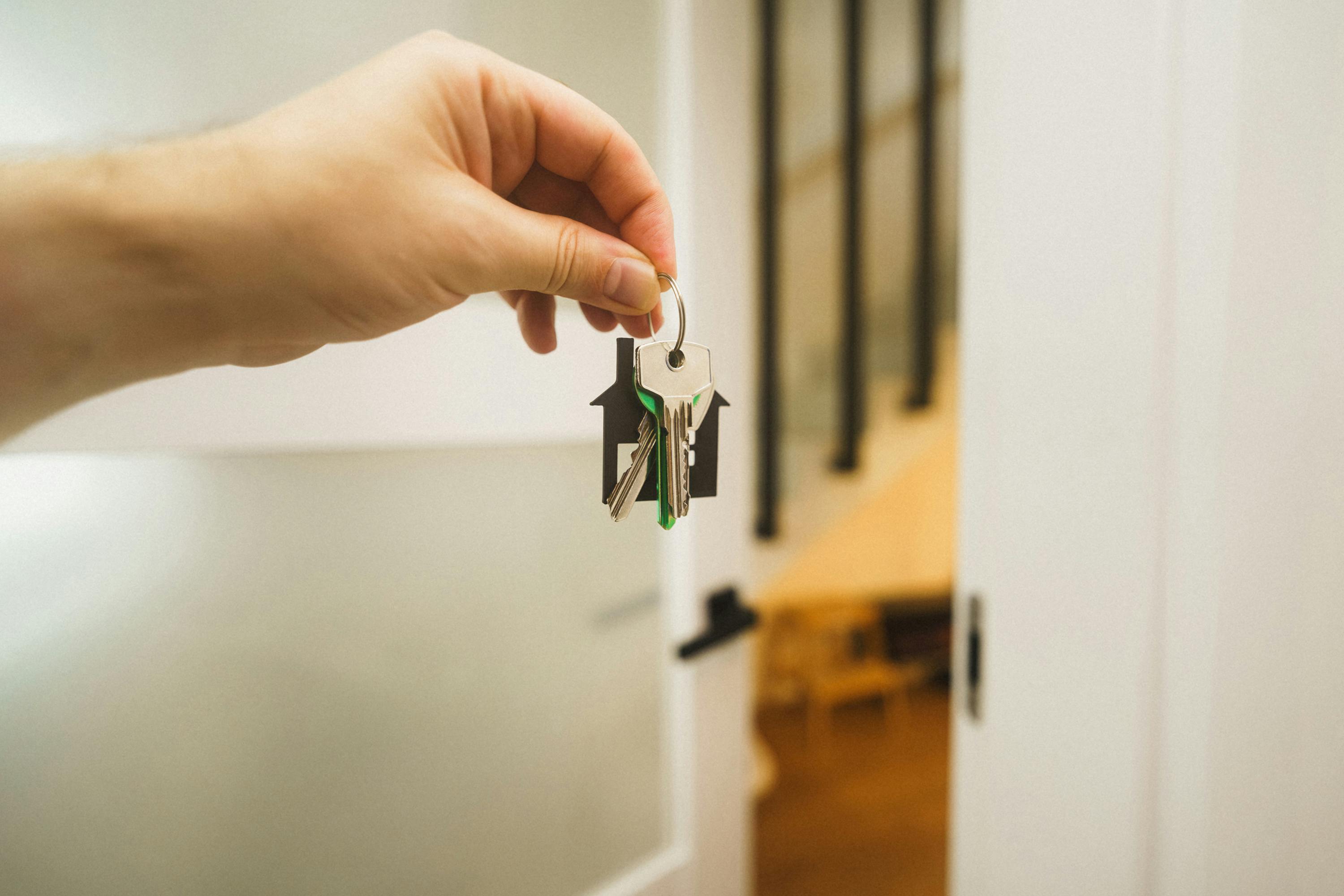 hand holding house key inside bright modern home