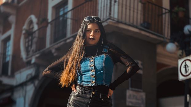 Trendy woman in denim jacket poses confidently in Heroica Puebla's urban setting.