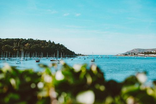 Free Boats floating on Conwy Bay, Wales, with a scenic view of lush greenery and clear blue skies. Stock Photo