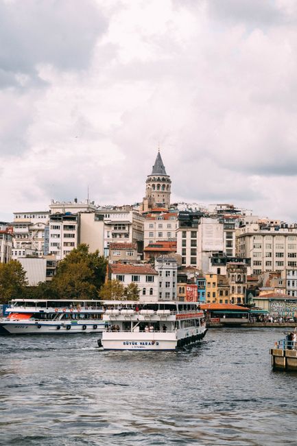 A picturesque view of Galata Tower with ferries on the Bosphorus, capturing Istanbul's vibrant architecture.