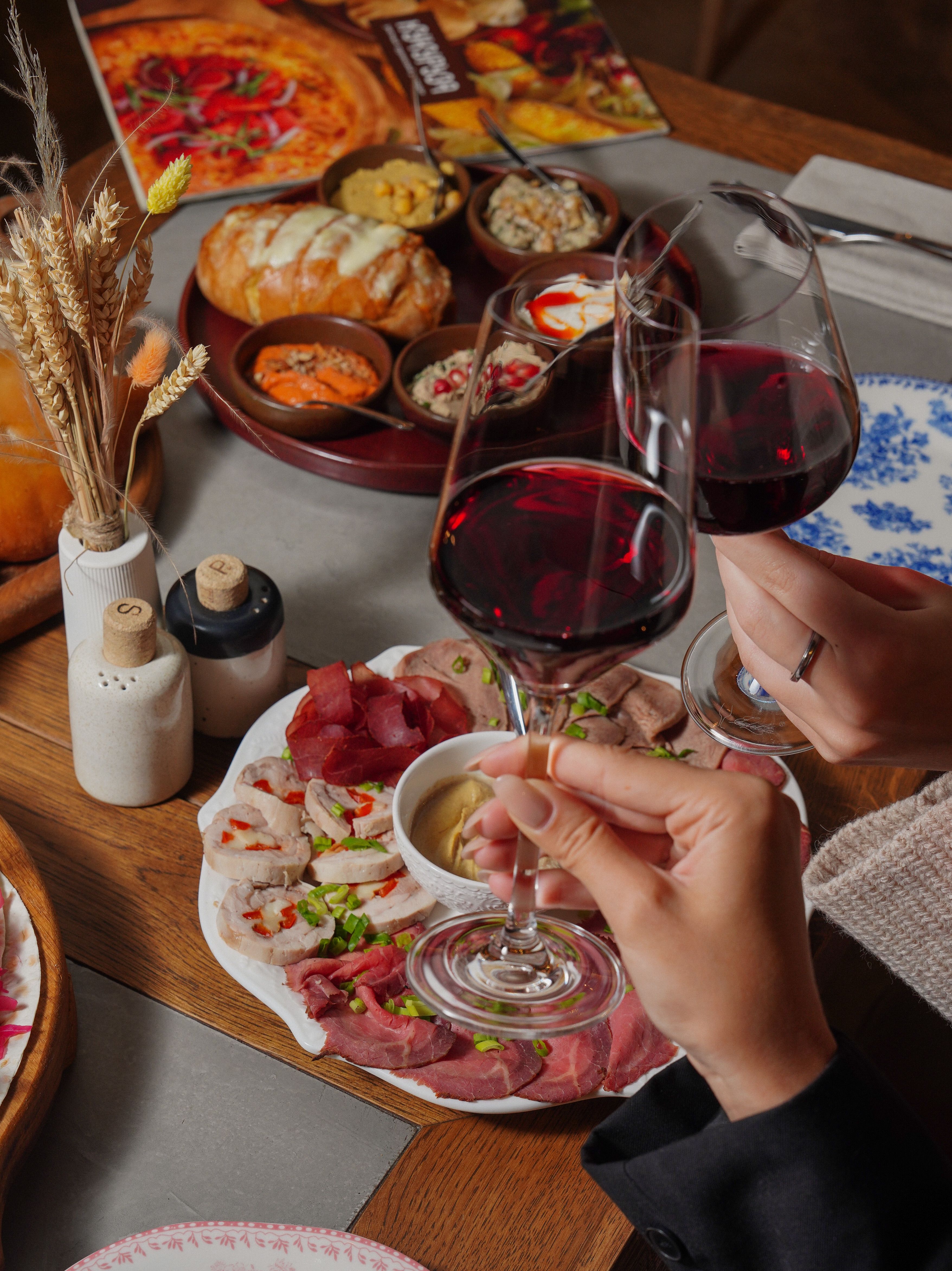 Free A cozy dinner setting with red wine and a variety of appetizers on a rustic wooden table. Stock Photo