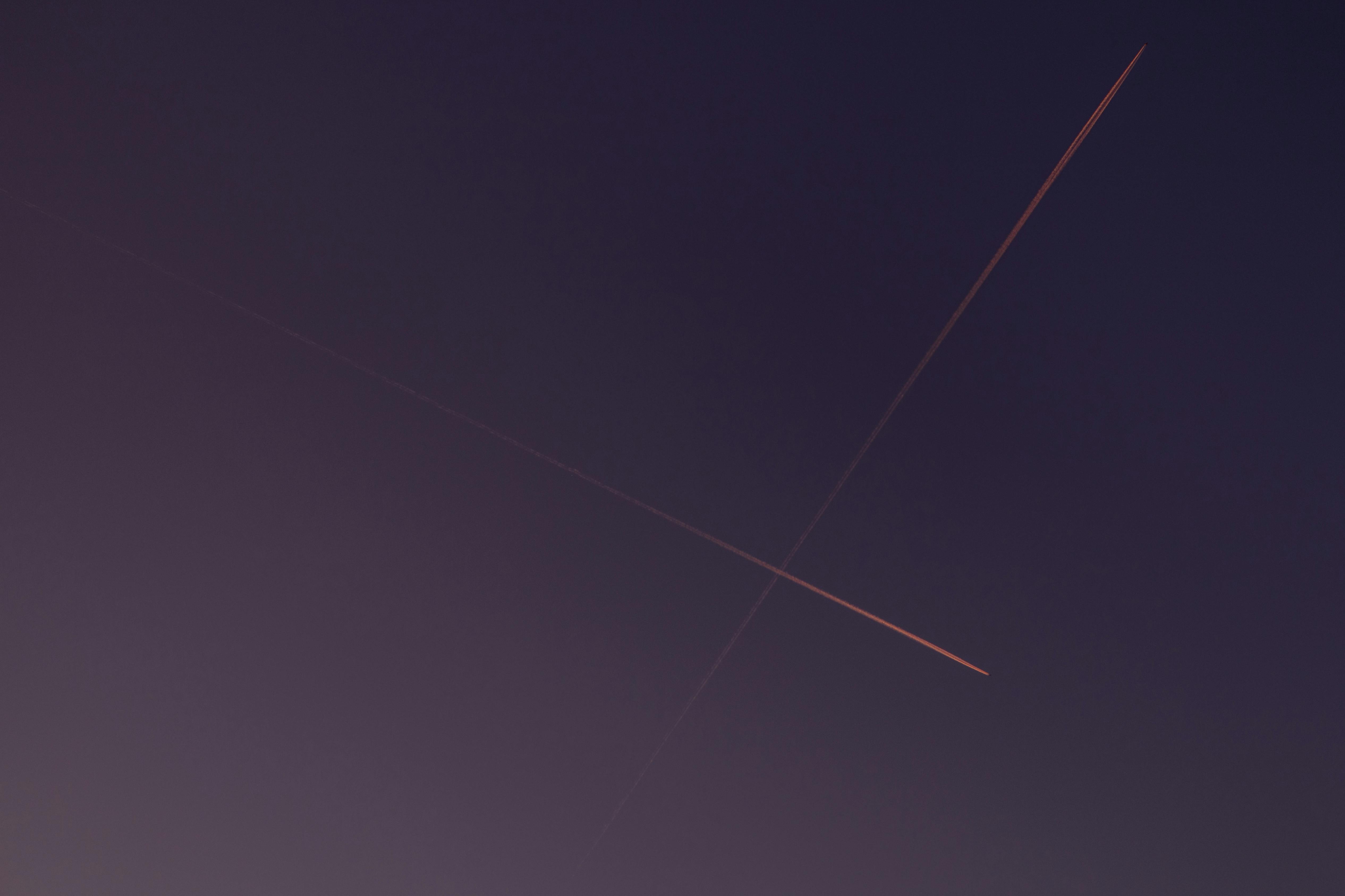 Gratis Un cielo vespertino sereno con estelas de condensación entrecruzadas, iluminadas por los tonos del atardecer. Foto de stock