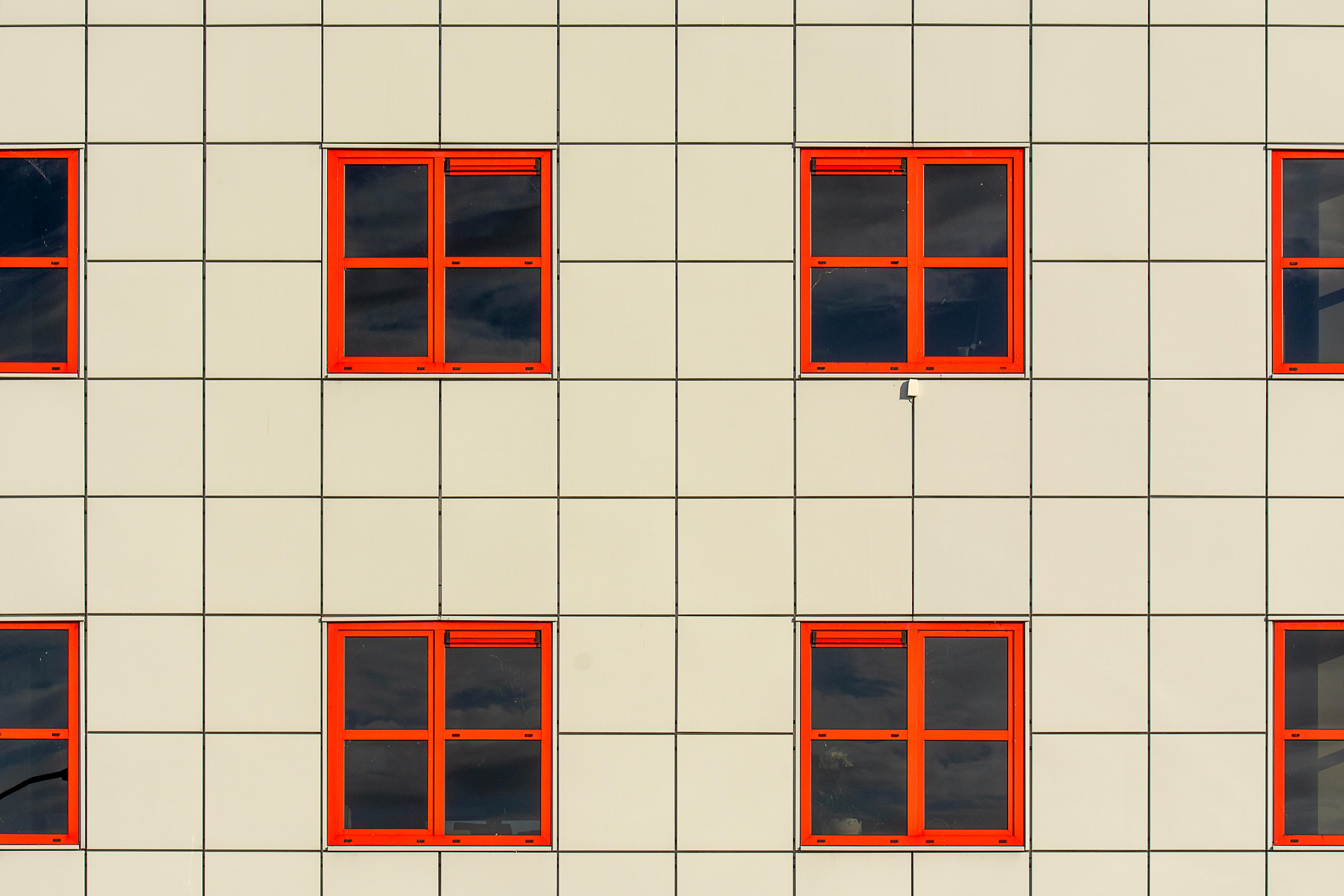 Close-up of a modern building facade featuring red-framed windows in a grid pattern.