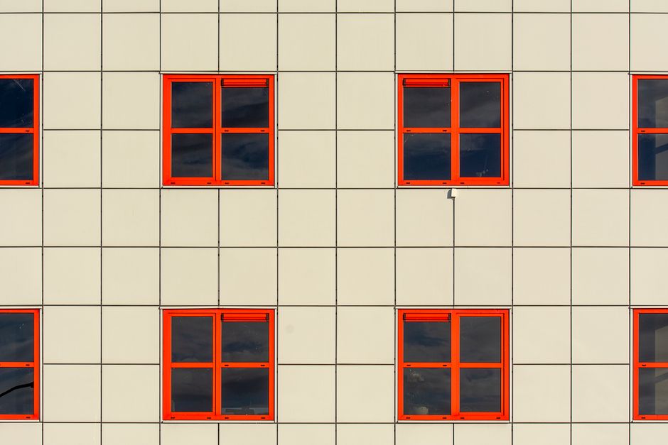 Close-up of a modern building facade featuring red-framed windows in a grid pattern.