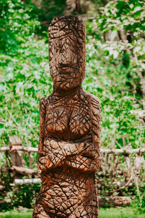 Free A detailed wooden statue stands in a vibrant green forest, showcasing traditional craftsmanship. Stock Photo
