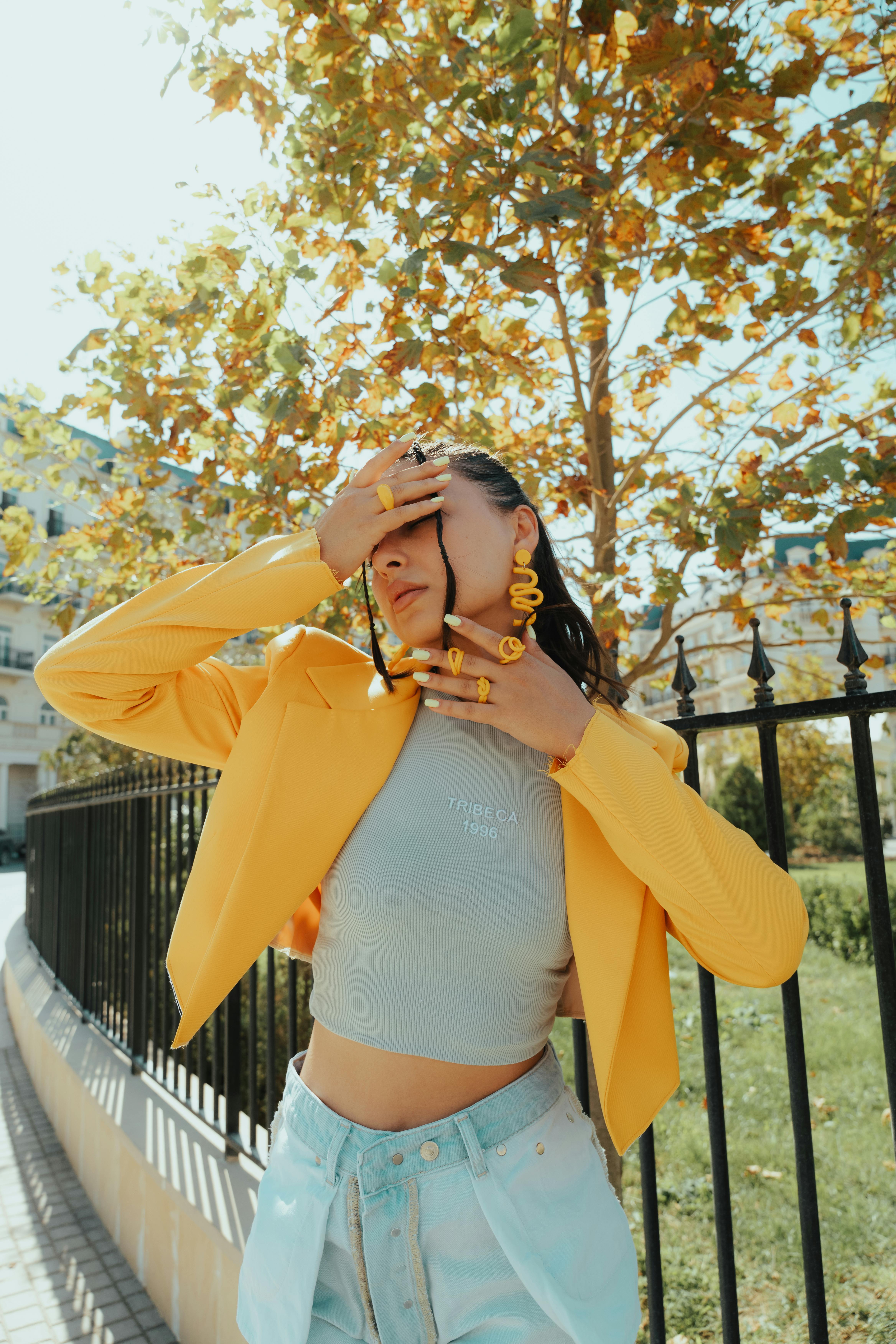 Fashionable woman in yellow jacket posing outdoors in Baku, exuding modern style in fall.