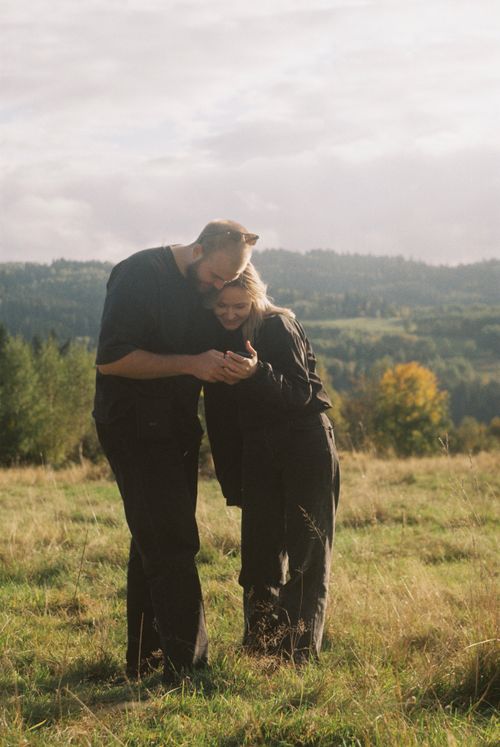 Free A couple enjoying a peaceful moment in a grassy field under a cloudy sky. Stock Photo