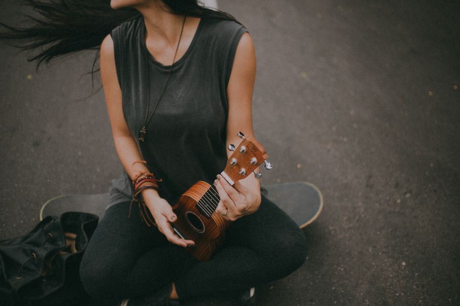 Woman playing a ukulele on a skateboard in Rio de Janeiro, Brazil.