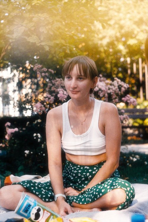 Free Young woman in white top and green skirt enjoying a summer picnic outdoors. Stock Photo