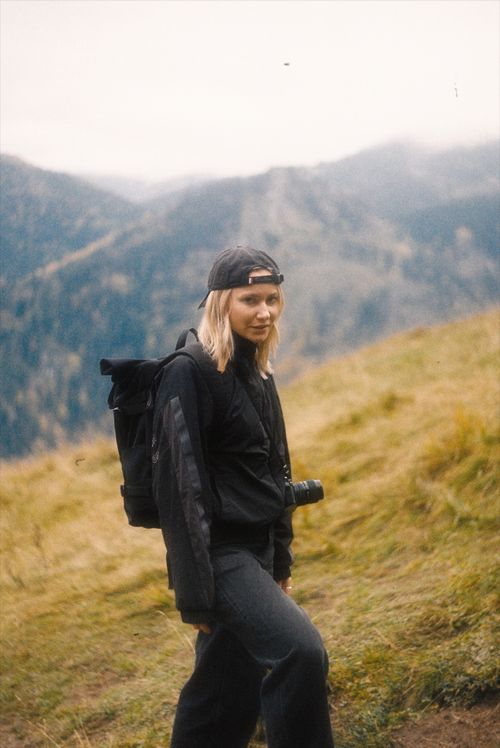 Free A woman with a backpack and camera hiking in a scenic mountain area. Stock Photo