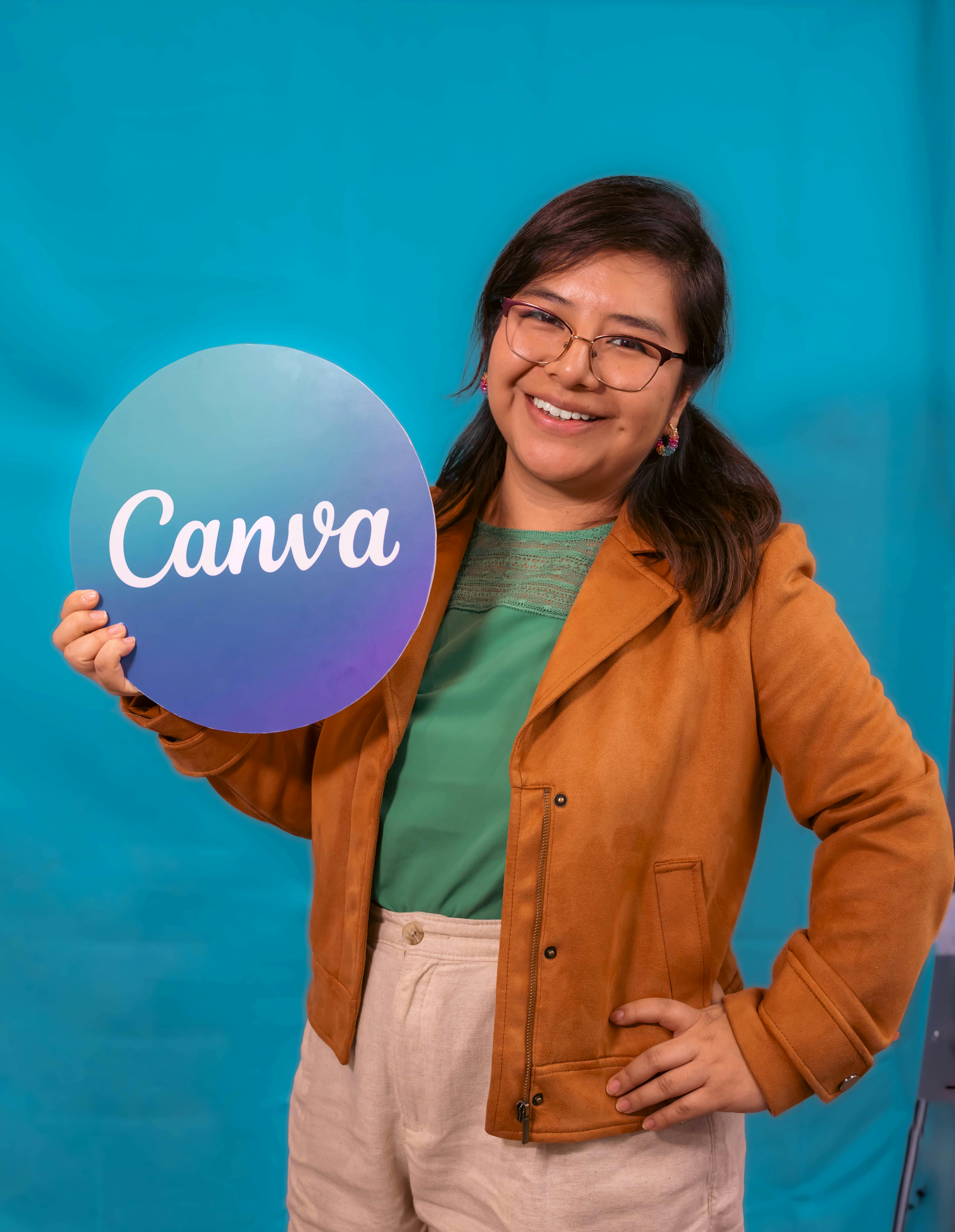 smiling woman holding canva sign on blue background