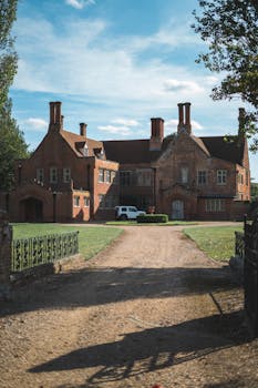 晴朗的天空下，矗立着一座优雅的砖砌豪宅，它有一条大车道，周围环绕着草坪