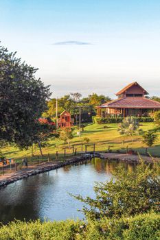 Picturesque rural landscape in Gravatá, Brazil with a serene pond, lush greenery, and traditional architecture.