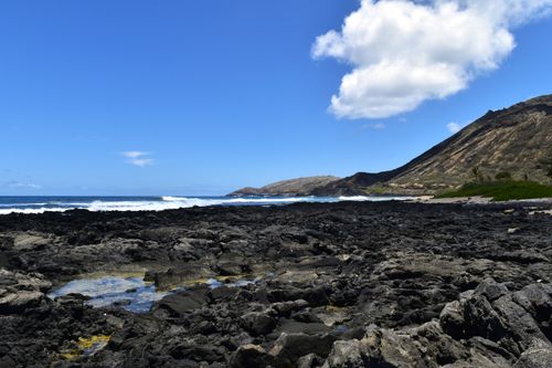 Free Scenic view of a rocky coastline with waves crashing and clear blue sky. Stock Photo
