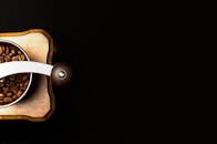 顶视图：黑色背景上，一台装满烤咖啡豆的木制咖啡研磨机