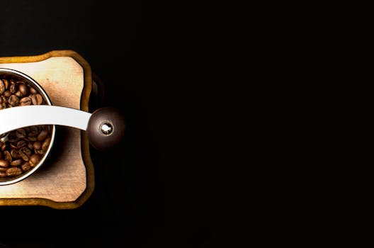 顶视图：黑色背景上，一台装满烤咖啡豆的木制咖啡研磨机