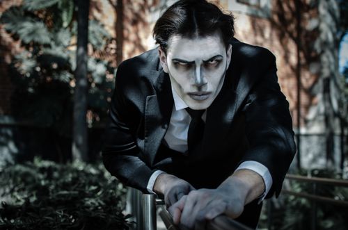 Free A man in a gothic Tim Burton-inspired costume poses dramatically outdoors, ideal for Halloween themes. Stock Photo